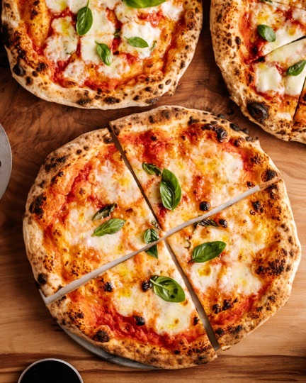 På billedet ses tre indbydende margherita pizzaer