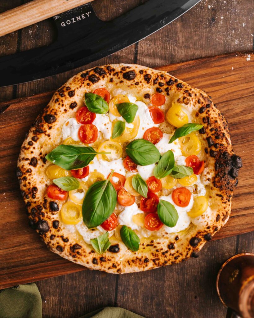 Her ses en gylden afbagt stenovn pizza med basilikum og tomat